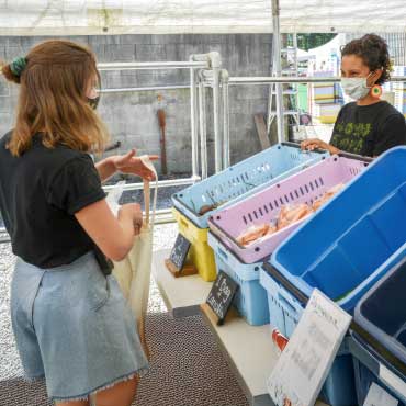 A vendor speaks to a customer at a produce stand