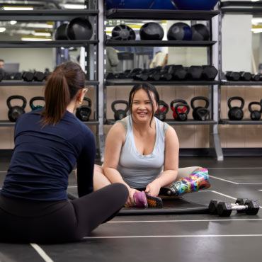 Two people sitting down cross-legged in a gym