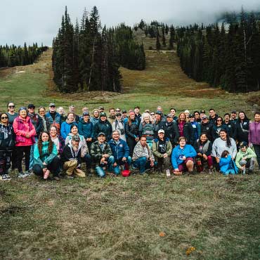 A Large group of people posing outside on a field in the fall