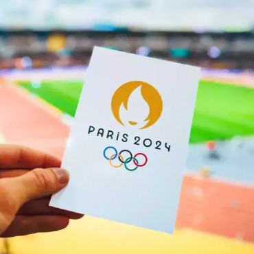 Person holding Paris Olympic book in a stadium