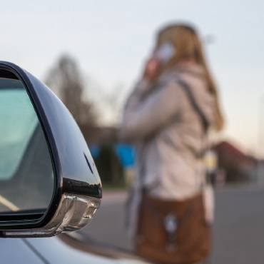 Person on the phone standing in front of car