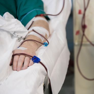 A patient lying in a hospital bed, connected to IVs, indicating medical care and recovery.