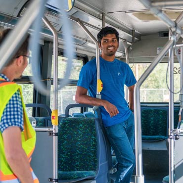 Two men are standing together a transit bus