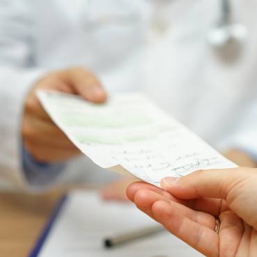 Doctor handing prescription slip to patient.