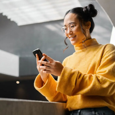 Person lookig at their mobile phone smiling.