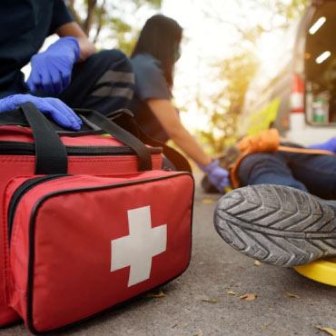 An individual on the ground next to an ambulance bag and paramedics.