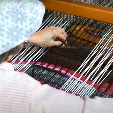 Person weaving a rug from a machine