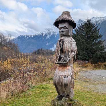 Nuxalk Nation totem pole standing tall against a clear blue sky