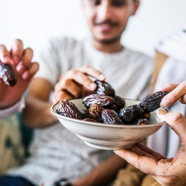 A group of people sharing a bowl of dates.