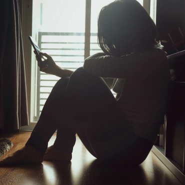 Person sitting on the floor in the dark